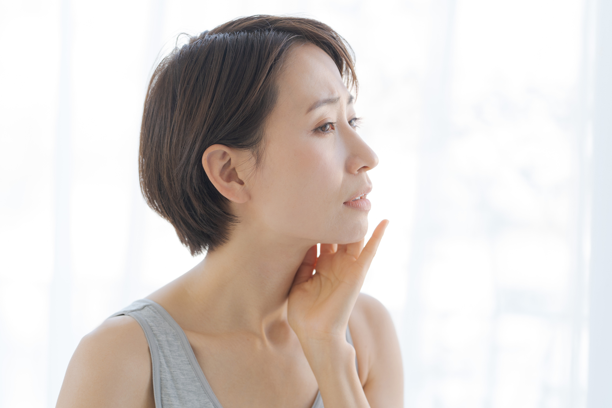 女性が顔を触っている画像